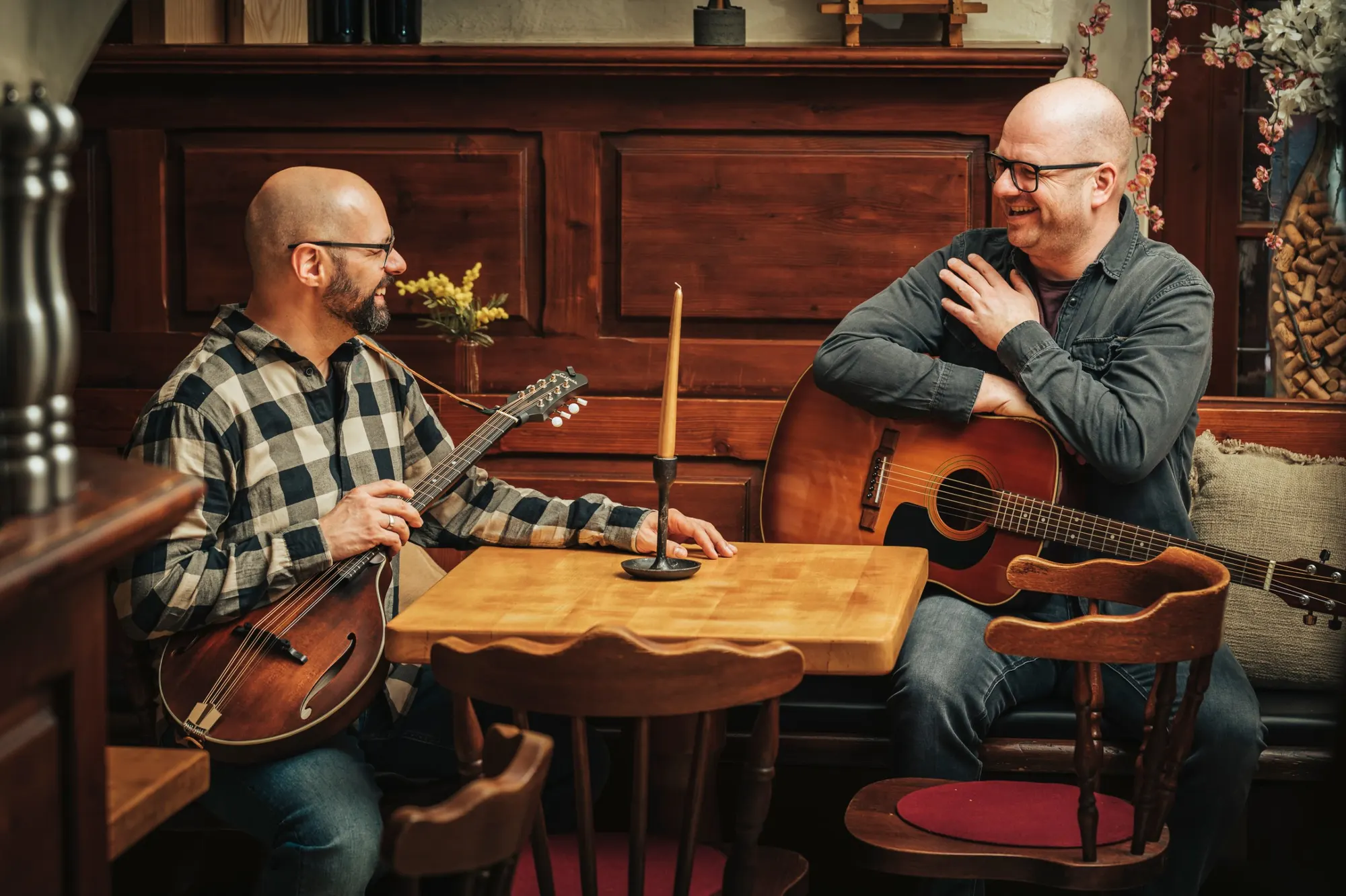 Akustik-Duo Silverweed: Alex mit Mandoline und Christian mit Gitarre lachend an einem Tisch in einer holzvertäfelten Gaststube