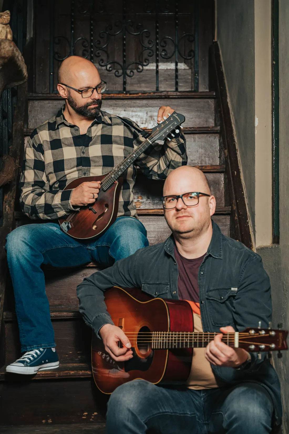 Silverweed buchen: Alex mit Mandoline und Christian mit Gitarre auf einer alten Holztreppe
