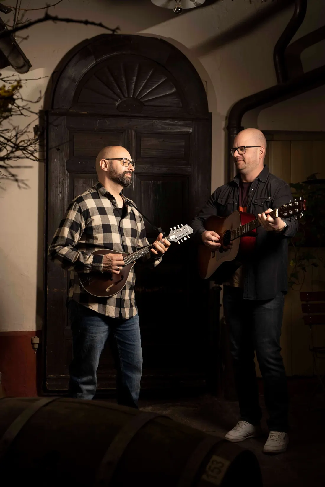 Silverweed live: Alex und Christian spielen Mandoline und Gitarre vor einer alten Holztür im Innenhof